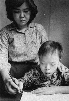 Child learning to write with the guidance of an adult