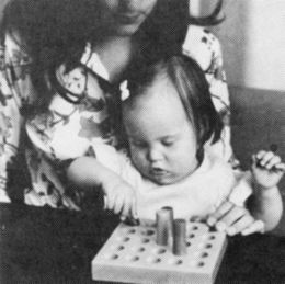 A child removing pegs sitting in an adults lap