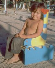 Foto de niño en asiento de madera.