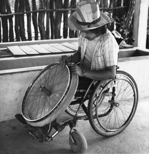 Hombre en silla de ruedas trabajando en una llanta.