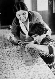 a boy putting pegs in holes while a woman watches.