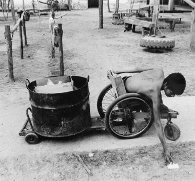 Niño en silla de ruedas recoge papel desechado.
