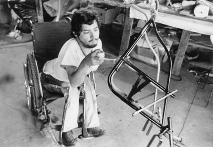 Hombre en silla de ruedas pintando estructura de metal.