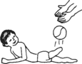 Small child lying on stomach, kicking ball backward with above the knee amputated leg.