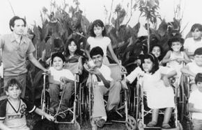Grupo de niños y niñas en sillas de ruedas y parados.