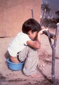 niño defecando en cuclillas aferrándose al apoyo